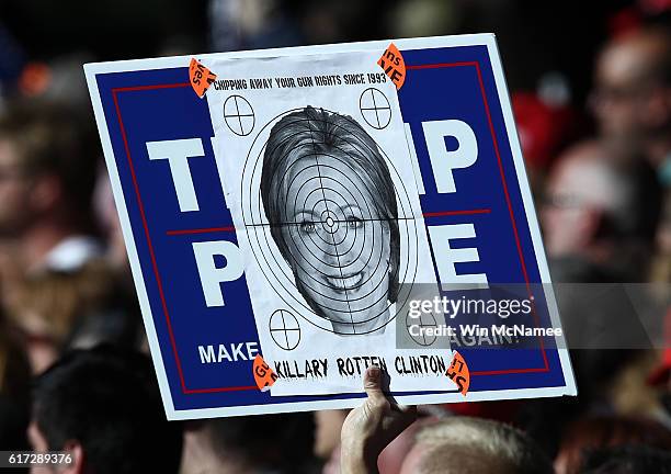 Supporter of Republican presidential candidate Donald Trump holds a picture of Democratic presidential candidate Hillary Clinton superimposed over a...