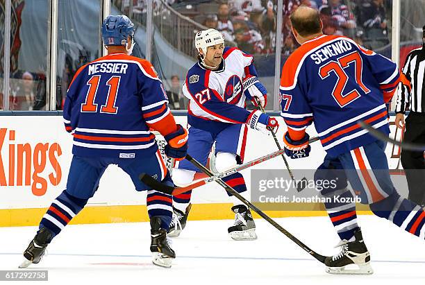 Mark Messier and Dave Semenko of the Edmonton Oilers alumni watch as Teppo Numminen of the Winnipeg Jets alumni passes the puck during first period...