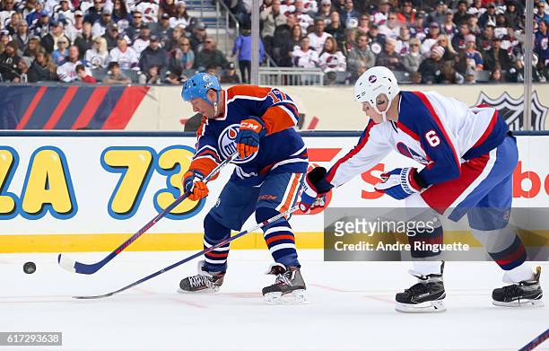 Jari Kurri of the Edmonton Oilers alumni pulls the puck away from Jim Kyte of the Winnipeg Jets alumni during the 2016 Tim Hortons NHL Heritage...