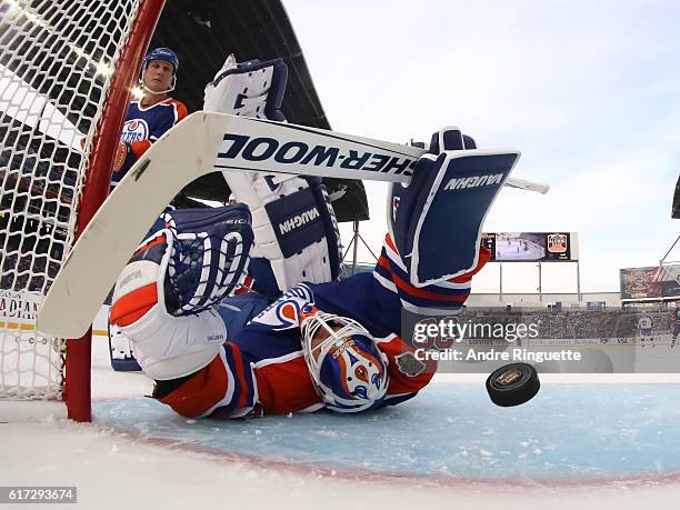 Winnipeg Jets alumni gets the puck past Bill Ranford of the Edmonton Oilers alumni during the 2016 Tim Hortons NHL Heritage Classic alumni game at...