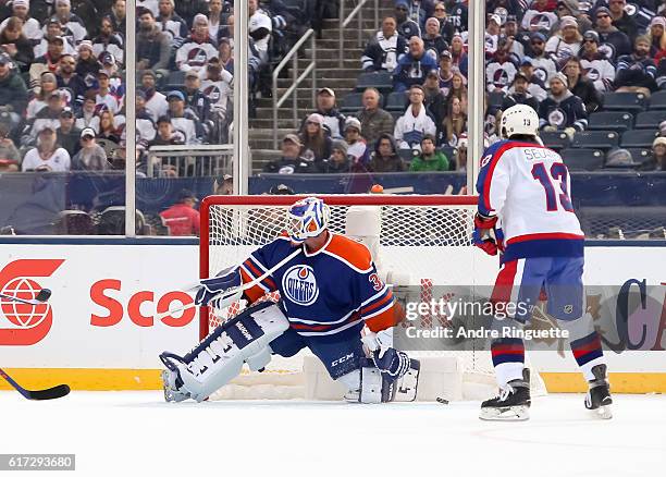 Winnipeg Jets alumni get the puck past Bill Ranford of the Edmonton Oilers alumni during the 2016 Tim Hortons NHL Heritage Classic alumni game at...