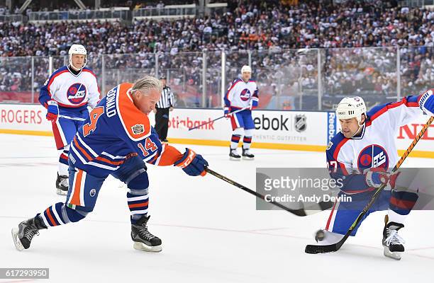 MacDonald of the Edmonton Oilers alumni fires a shot with pressure from Teppo Numminen of the Winnipeg Jets alumni during the 2016 Tim Hortons NHL...