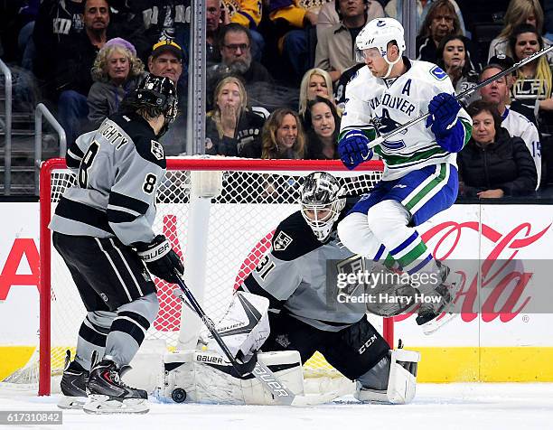 Peter Budaj of the Los Angeles Kings makes a save as Daniel Sedin of the Vancouver Canucks jumps out of the way in front of Drew Doughty during the...