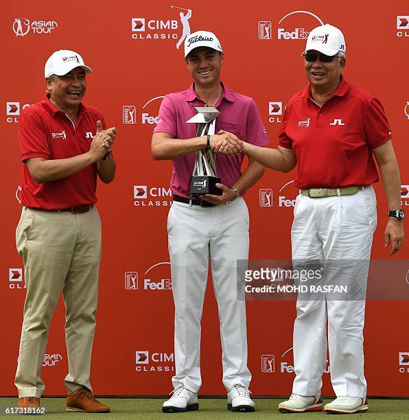 Justin Thomas of the US shakes hands with Malaysia's Prime Minister Najib Razak as Chairman of CIMB Group Nazir Razak applauds during the prize...