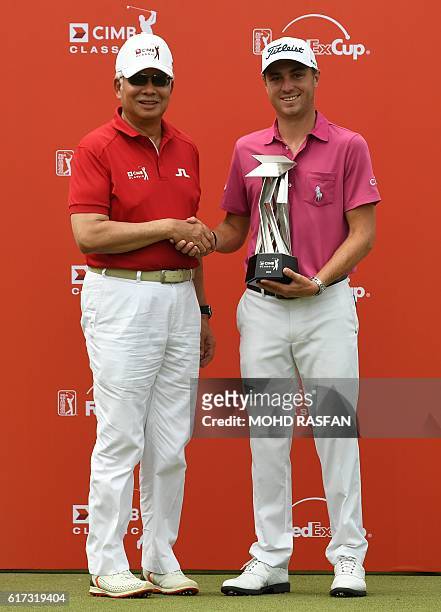 Justin Thomas of the US shakes hands with Malaysia's Prime Minister Najib Razak as they pose for pictures during the awards ceremony after Thomas's...