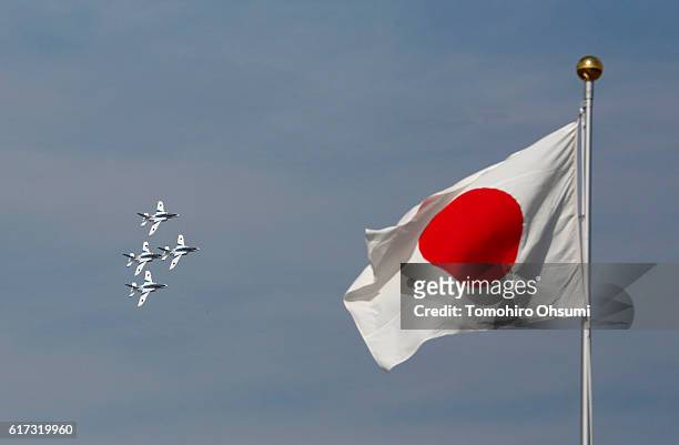 Japanese national flag flies as aircrafts from Japan's Air Self-Defense Force's acrobatic flight team, known as Blue Impulse, fly during the annual...