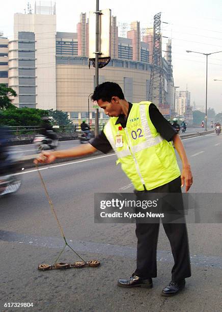 Indonesia - A member of a volunteer group working to remove ''nail land mines'' in Jakarta collects nails with a hand-made tool using a magnet on a...