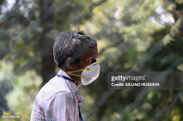 An Indian worker wears a mask as he sits inside the entry gate of the Deer Park, which is temporarily closed for visitors as a precautionary measure...