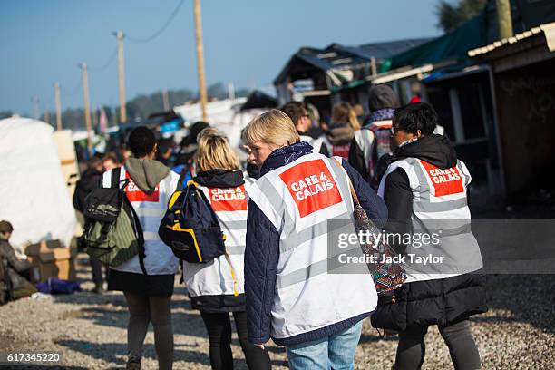 Volunteers from the Care 4 Calais charity walk through the Jungle migrant camp on October 23, 2016 in Calais, France. Volunteers and officials have...