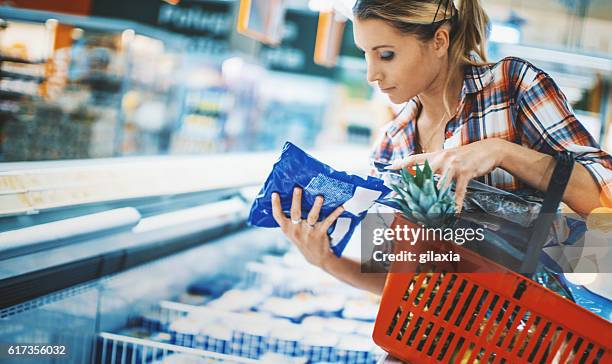 mujer bying algunos alimentos congelados en un supermercado. - frozen food fotografías e imágenes de stock