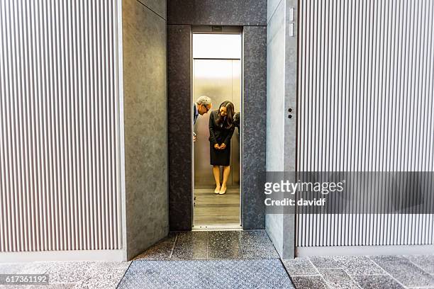 english businessman with japanese corporate professional women in office elevator - japanese greeting stock pictures, royalty-free photos & images