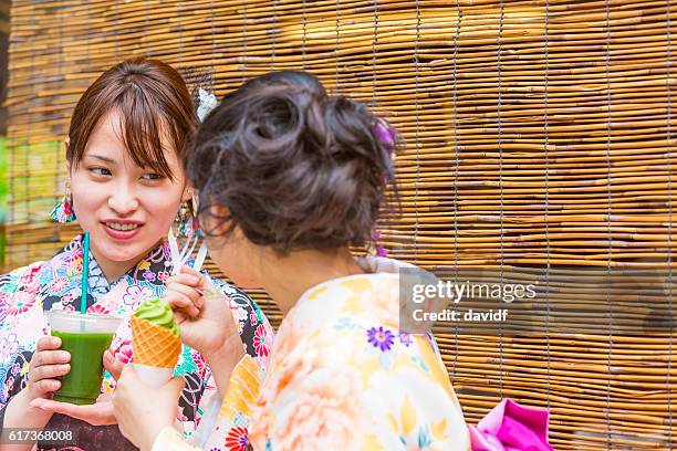 kimono wearing young japanese women with matcha tea ice cream - geisha eating stockfoto's en -beelden