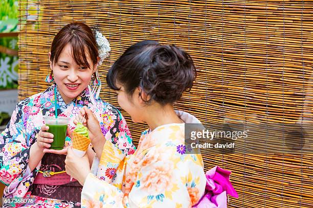 kimono wearing young japanese women with matcha tea ice cream - geisha eating stockfoto's en -beelden