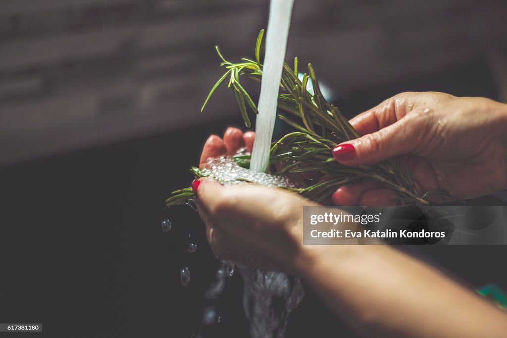 Woman rinsing rosemary in the kitchen