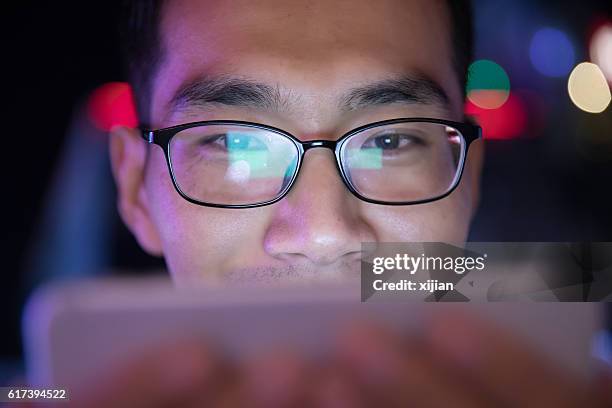 hombre de primer plano usando el teléfono móvil por la noche - pantalla de proyección fotografías e imágenes de stock