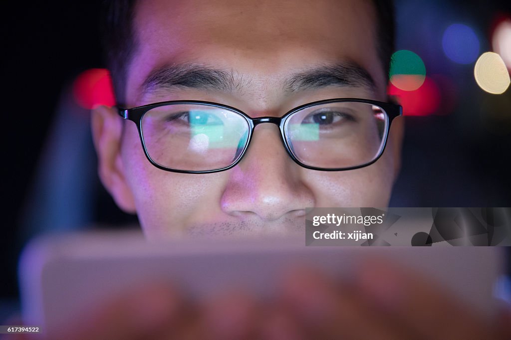 Close-up man using mobile phone at night