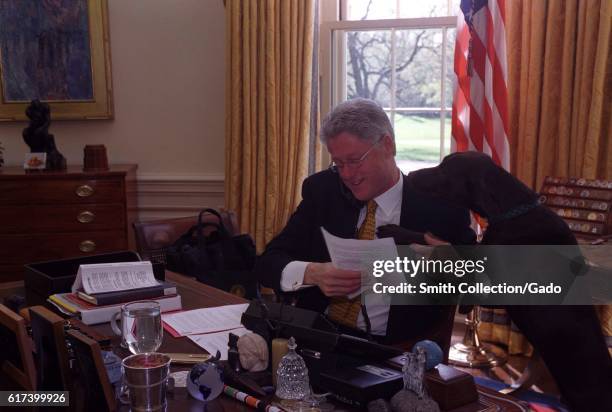 President William Jefferson Clinton sitting at his desk and on the phone with Russian President Boris Yeltsin, Buddy the Dog resting head on his...