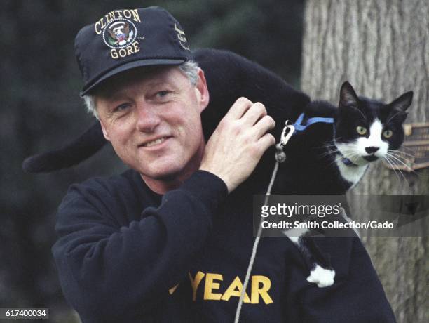 President Bill Clinton, wearing pullover sweatshirt and a Clinton-Gore administration baseball hat, smiles while taking a walk on the White House...