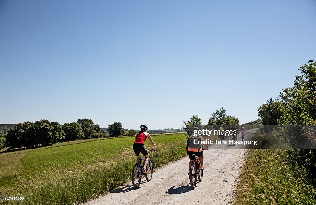 Friends cycling on road against clear sky