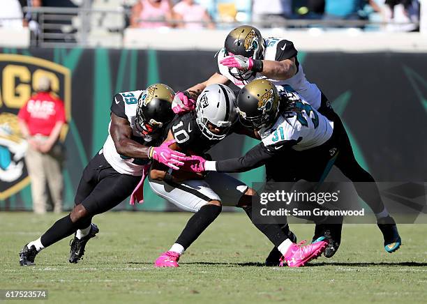 Davon House, Tashaun Gipson and Paul Posluszny of the Jacksonville Jaguars converge on Seth Roberts of the Oakland Raiders during the game at...