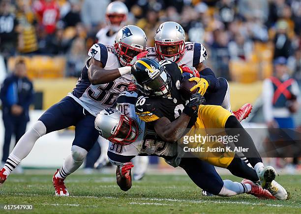 Le'Veon Bell of the Pittsburgh Steelers is tackled by Devin McCourty, Duron Harmon and Malcolm Butler of the New England Patriots in the first half...