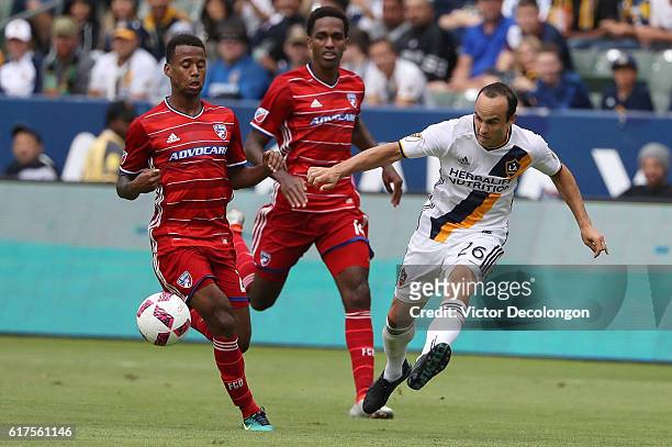 Landon Donovan of the Los Angeles Galaxy crosses the ball as Kellyn Acosta and Atiba Harris of FC Dallas pursue the play during their MLS match at...