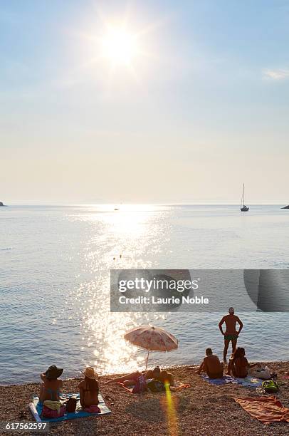 people sitting on beach, sivota - epirus greece stock pictures, royalty-free photos & images