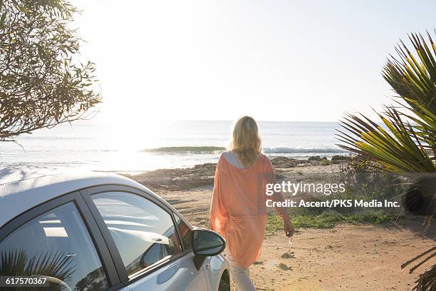 view past car door as woman walks across beach - tunic woman stock pictures, royalty-free photos & images