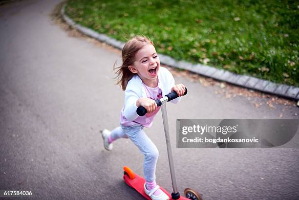 girl riding push scooter - push scooter stock pictures, royalty-free photos & images