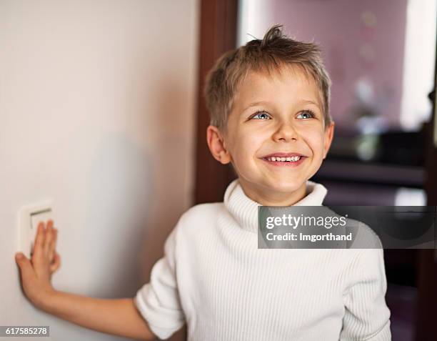 little boy turning on light - turning on or off imagens e fotografias de stock