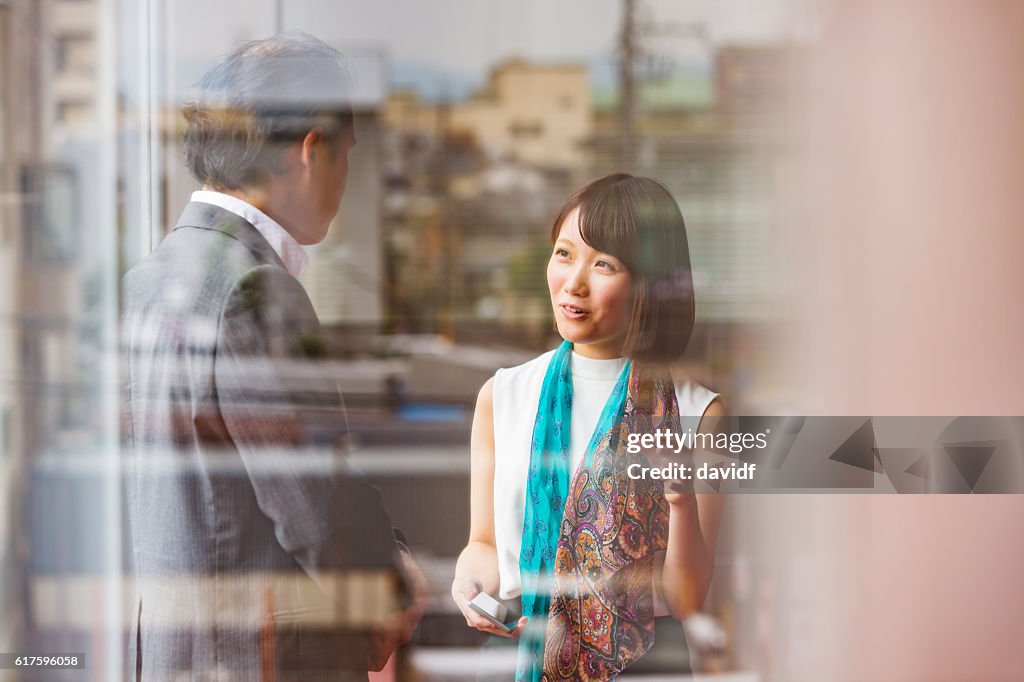 Japanese Business Man and Woman Meeting Viewed Through Office Window