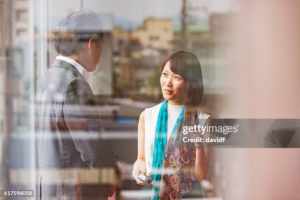 japanese business man and woman meeting viewed through office window - on the outside looking in stock pictures, royalty-free photos & images