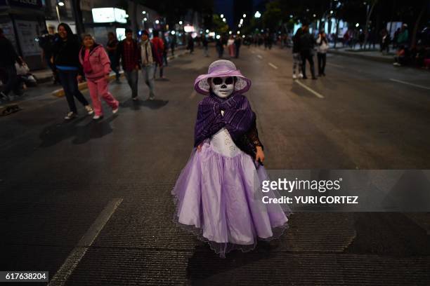 Girl dressed as "Catrina" walks while taking part in the "Catrinas Parade" along Reforma Avenue, in Mexico City on October 23, 2016. - Mexicans get...