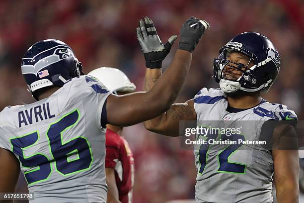 Defensive end Michael Bennett of the Seattle Seahawks high fives Cliff Avril after a defensive stop against the Arizona Cardinals during the second...