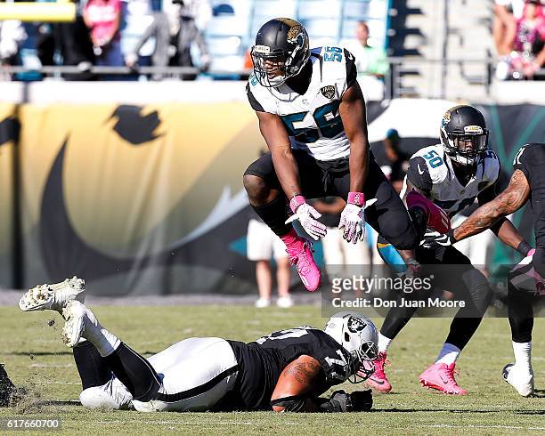 Defensive End Dante Fowler Jr. #56 of the Jacksonville Jaguars avoids a low block by leaping over Tackle Austin Howard of the Oakland Raiders during...