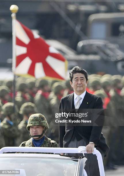 Japanese Prime Minister, standing in a convertible, attends an annual troop review of Japan's Self-Defense Forces at the Asaka garrison of the Ground...