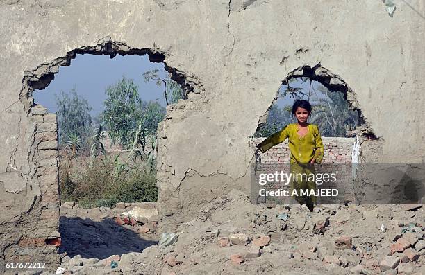 An Afghan refugee girl stands on the debris of a demolish house in khazana refugees camp outskirts of Peshawar on October 24, 2016. More than 350,000...