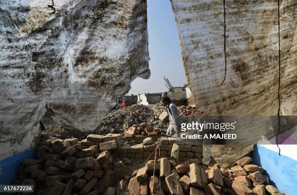 An Afghan refugee shifts bricks after demolishing his house before return his home land under the UNHCR voluntary programme in khazana refugees camp...