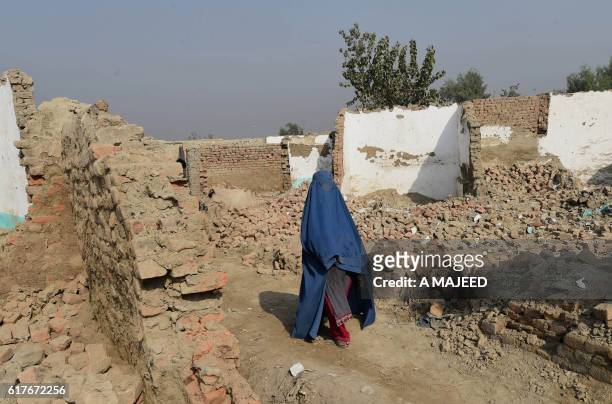 Burqa wearing Afghan refugee woman crosses a demolish houses in khazana refugees camp outskirts of Peshawar on October 24, 2016. More than 350,000...