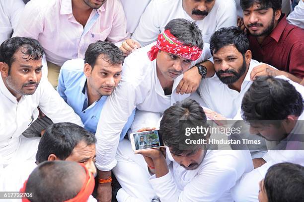 Supporters of Uttar Pradesh Chief Minister Akhilesh Yadav listen to news outside party office during an internal Samajwadi Party meeting to resolve...