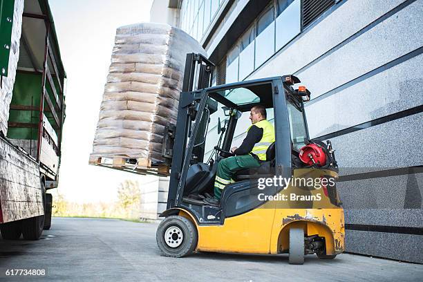 worker loading pallet with a forklift into a truck. - forklift outside stock pictures, royalty-free photos & images
