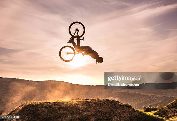 hábil ciclista haciendo backflip contra el cielo al atardecer. - backflipping fotografías e imágenes de stock