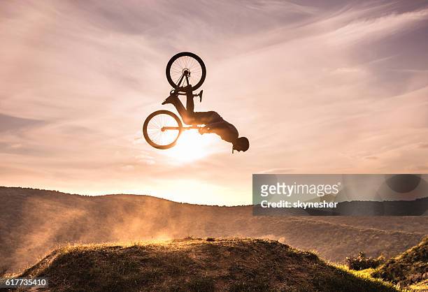 abile ciclista che fa backflip contro il cielo al tramonto. - extreme foto e immagini stock