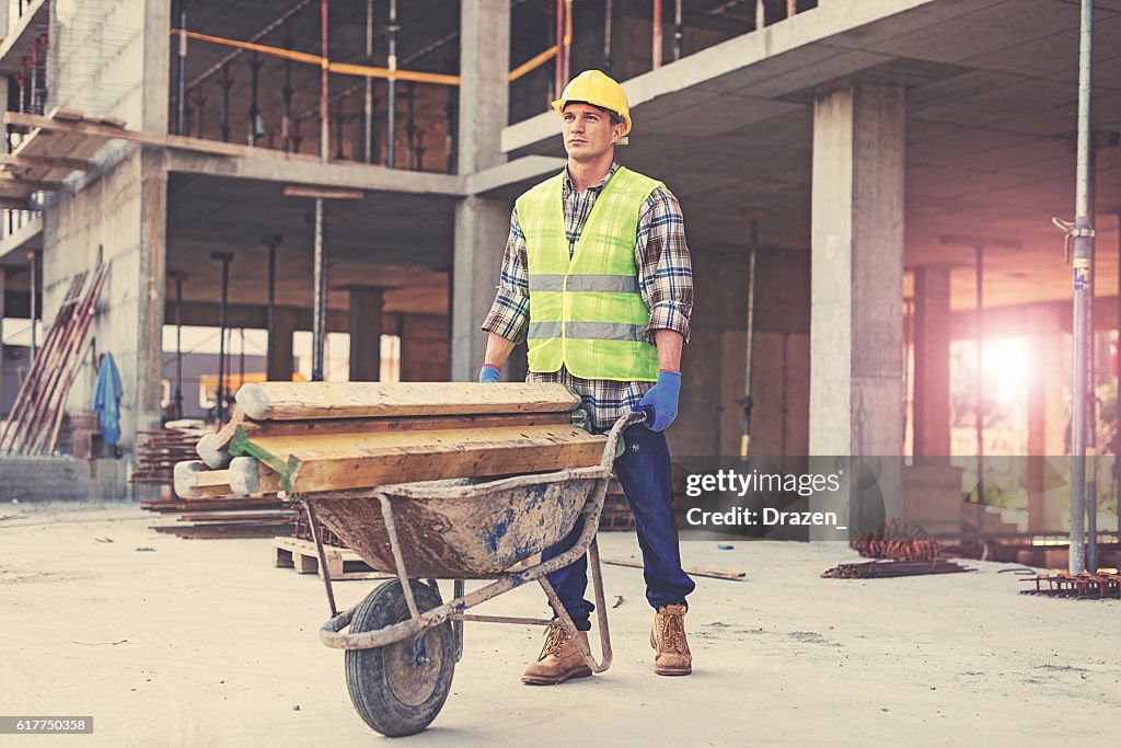 Travailleur De La Construction En Vêtements Réfléchissants Poussant Une  Brouette Photo - Getty Images