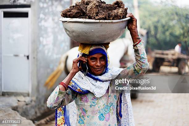 old women carrying cow dung and talking on phone - rural india stock pictures, royalty-free photos & images