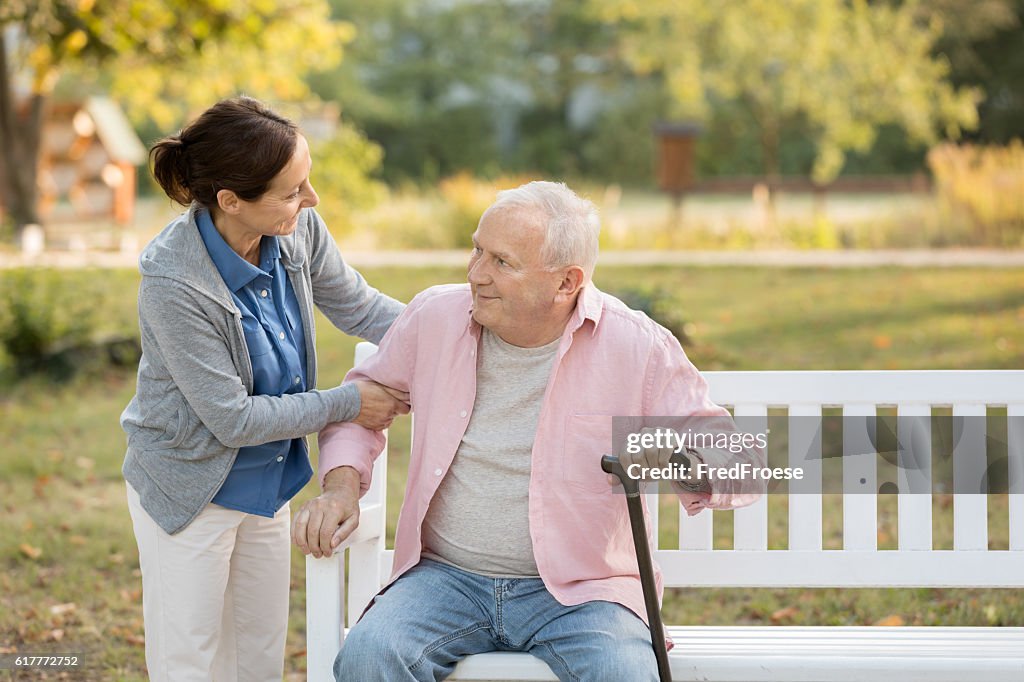 Caregiver and senior man in the park on park bench