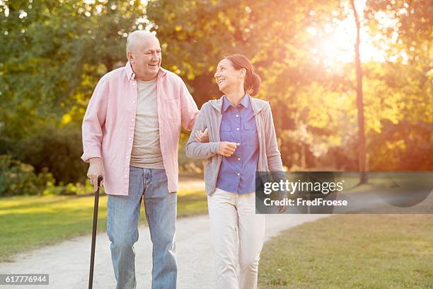 donna anziana e caregiver andare a piedi all'aperto - bastone foto e immagini stock