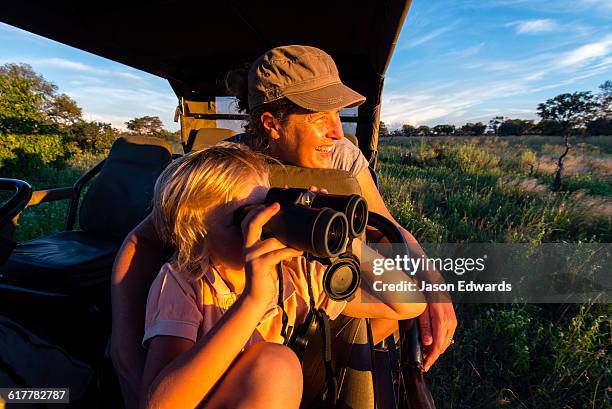 a mother and son in a safari 4wd watching wildlife. - safari photos et images de collection