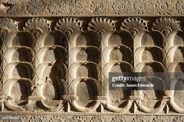 a limestone frieze of lotus flowers carved into a stone wall at persepolis. - bas-relief stock pictures, royalty-free photos & images