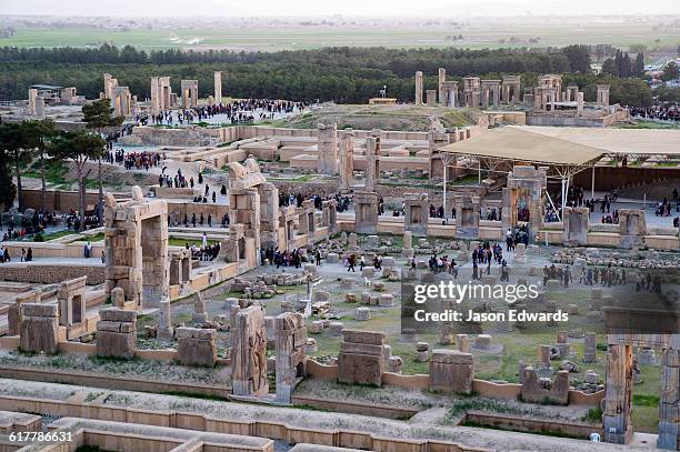 tourists move through the ruins of persepolis during the sunset afterglow. - persepolis stock pictures, royalty-free photos & images